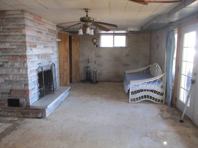 basement with a stone fireplace and ceiling fan