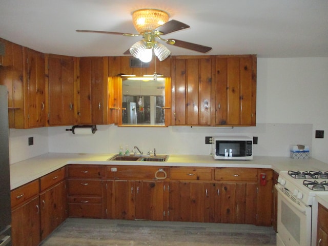 kitchen with white appliances, light hardwood / wood-style floors, ceiling fan, and sink