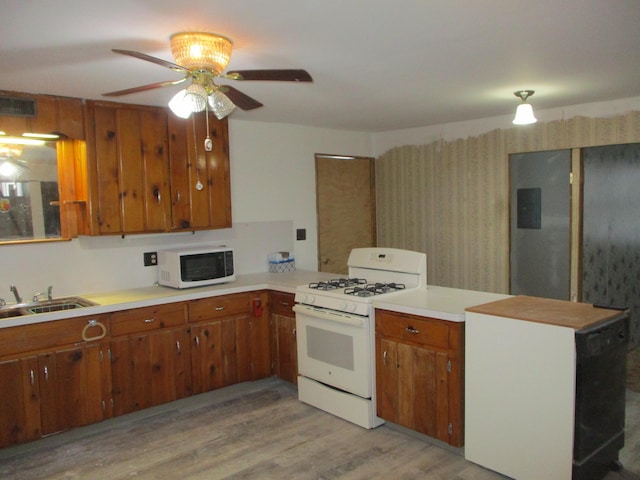 kitchen with white appliances, sink, ceiling fan, light hardwood / wood-style floors, and kitchen peninsula