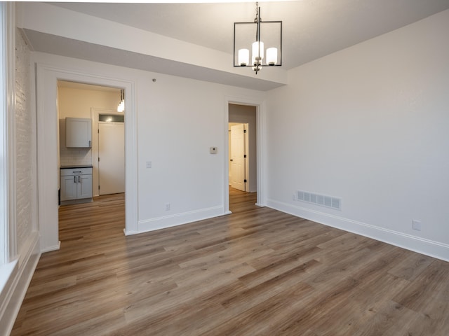 unfurnished room featuring light hardwood / wood-style floors and an inviting chandelier