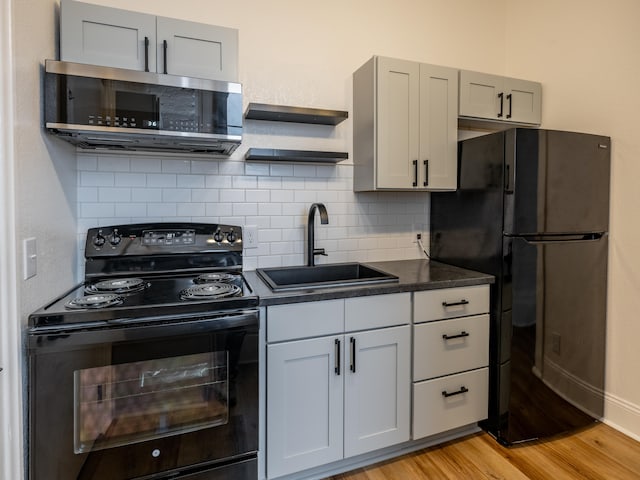 kitchen with backsplash, black appliances, sink, gray cabinets, and light wood-type flooring