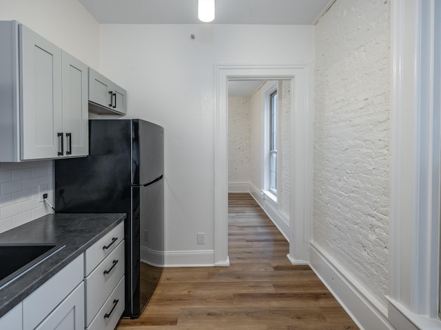 kitchen with hardwood / wood-style floors, black fridge, sink, gray cabinets, and tasteful backsplash