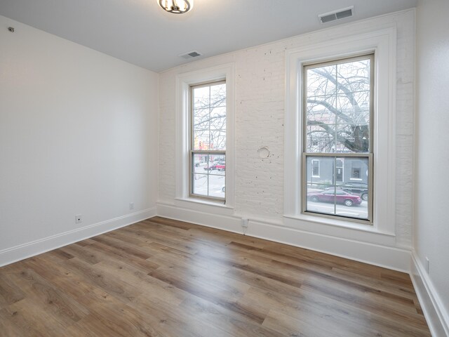 empty room with hardwood / wood-style flooring and a wealth of natural light