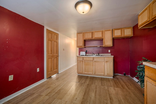 kitchen with light brown cabinetry, sink, and light wood-type flooring