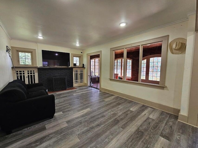 living room featuring crown molding, dark wood-type flooring, and a brick fireplace