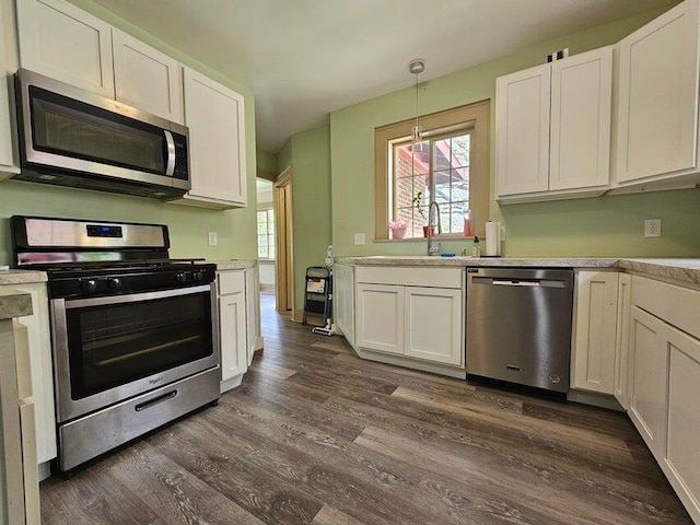 kitchen featuring sink, white cabinetry, stainless steel appliances, pendant lighting, and dark hardwood / wood-style floors