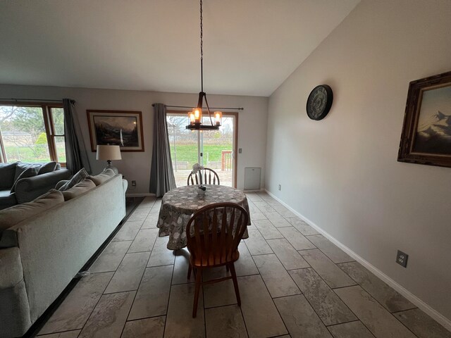 dining room with a wealth of natural light, wood-type flooring, vaulted ceiling, and an inviting chandelier