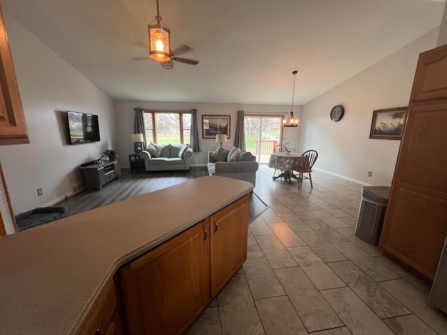 kitchen with ceiling fan with notable chandelier, hanging light fixtures, light wood-type flooring, and vaulted ceiling