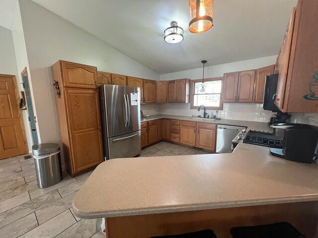 kitchen featuring lofted ceiling, kitchen peninsula, decorative backsplash, appliances with stainless steel finishes, and decorative light fixtures