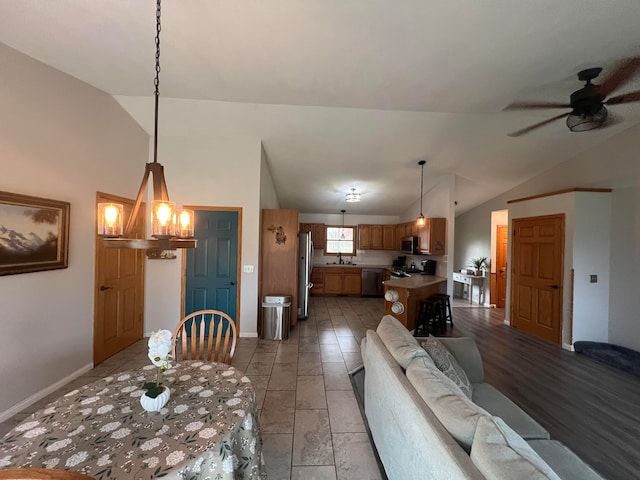 dining room featuring ceiling fan with notable chandelier, lofted ceiling, and sink