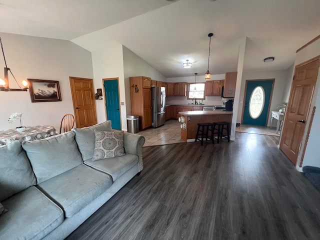 living room featuring dark wood-type flooring, vaulted ceiling, and a notable chandelier