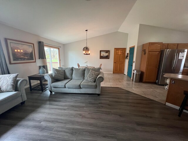 living room featuring dark wood-type flooring, vaulted ceiling, and an inviting chandelier