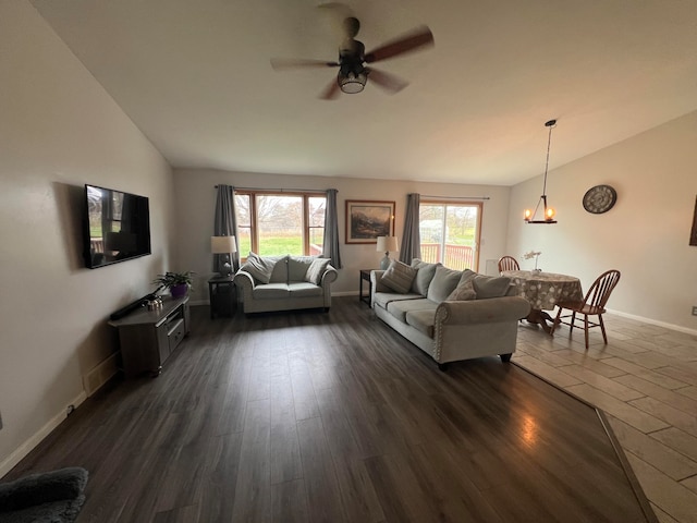 living room with ceiling fan with notable chandelier, dark hardwood / wood-style floors, and vaulted ceiling