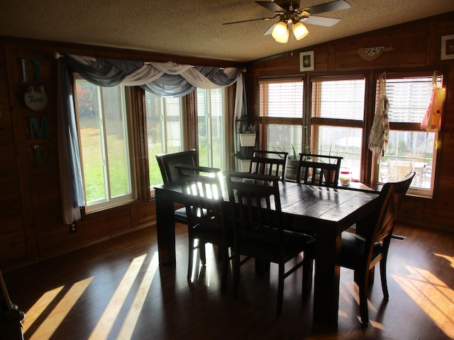 dining room with wooden walls, ceiling fan, dark hardwood / wood-style floors, and vaulted ceiling