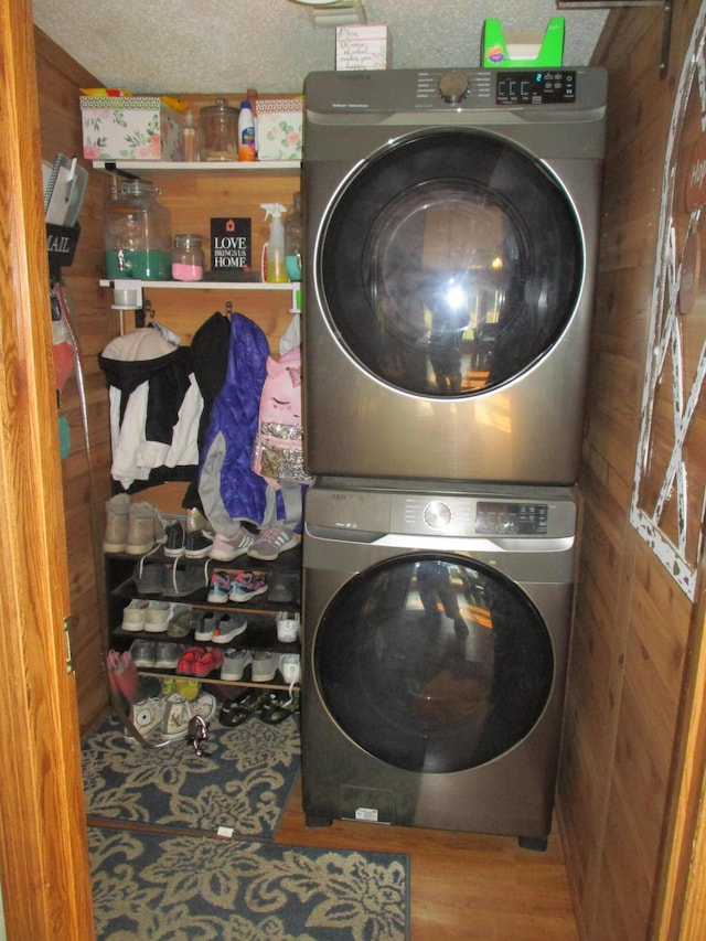 laundry area featuring stacked washer and clothes dryer and wood walls