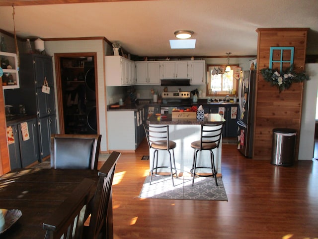 kitchen featuring a breakfast bar, dark wood-type flooring, ornamental molding, white cabinetry, and stainless steel appliances