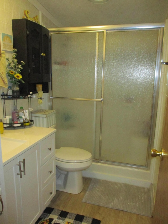 bathroom with vanity, toilet, wood-type flooring, and walk in shower