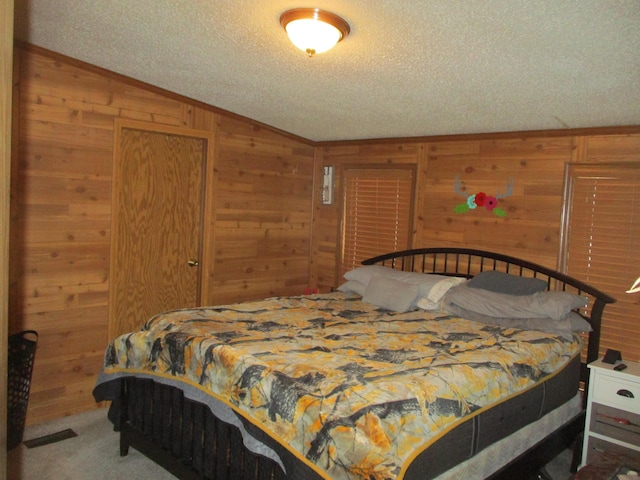 carpeted bedroom with wooden walls and a textured ceiling