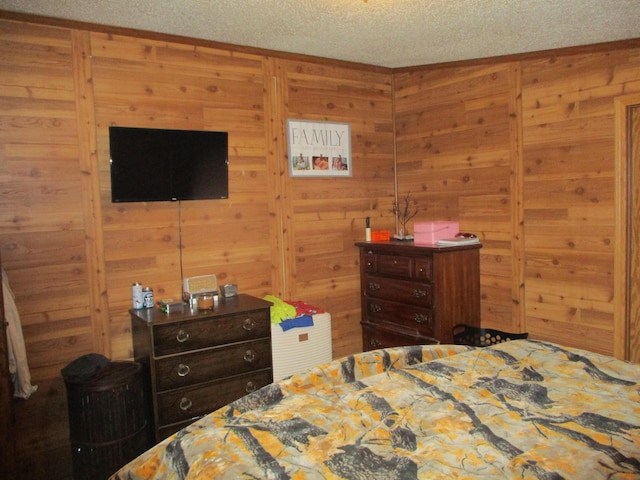 bedroom featuring a textured ceiling and wooden walls