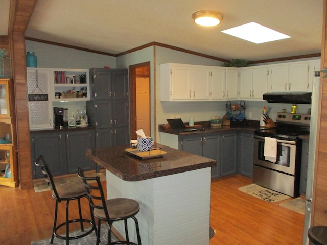 kitchen with electric range, gray cabinetry, vaulted ceiling with skylight, and a breakfast bar area