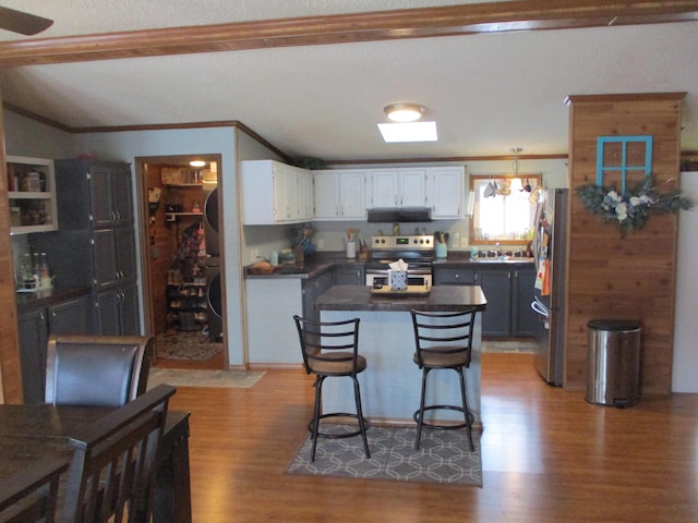 kitchen featuring a kitchen bar, dark hardwood / wood-style flooring, white cabinets, and appliances with stainless steel finishes