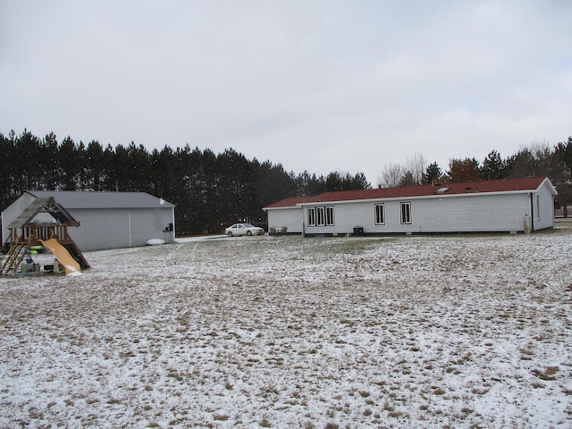 snow covered rear of property with a playground