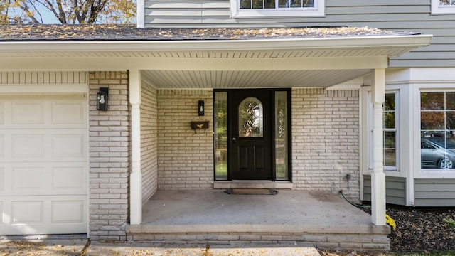 view of exterior entry with a garage and a porch