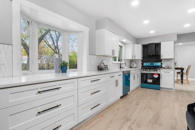 kitchen with light hardwood / wood-style flooring, white cabinets, wall chimney range hood, and stainless steel appliances