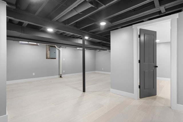 basement featuring light hardwood / wood-style floors and electric panel