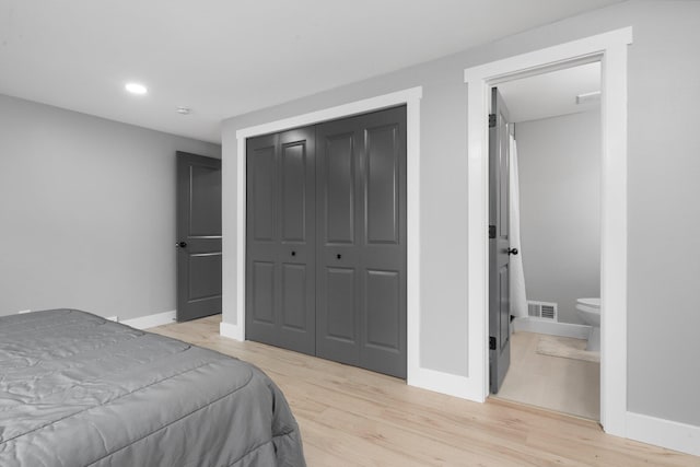 bedroom with a closet, ensuite bath, and light hardwood / wood-style flooring