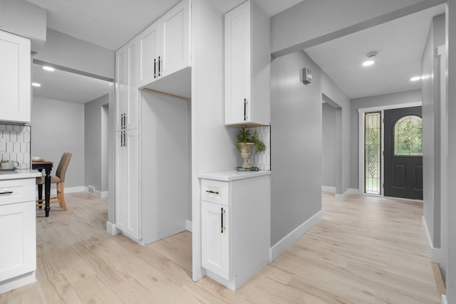 kitchen with white cabinetry, light hardwood / wood-style floors, and tasteful backsplash