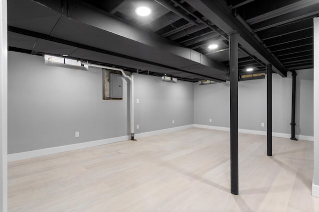 basement featuring electric panel and light wood-type flooring