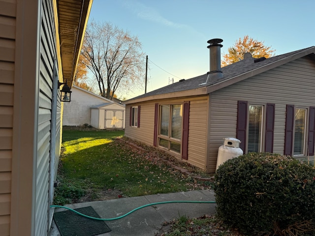 view of side of property with a storage unit and a lawn