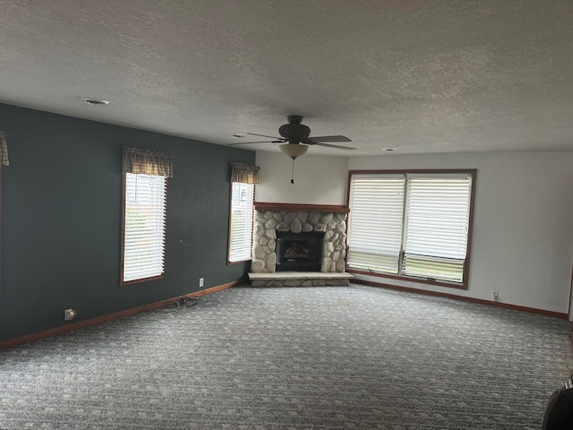 unfurnished living room with a textured ceiling, ceiling fan, a fireplace, and carpet floors