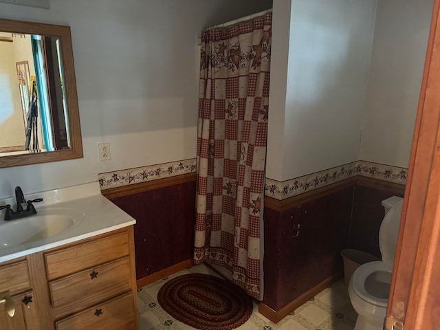 bathroom featuring toilet, walk in shower, and vanity