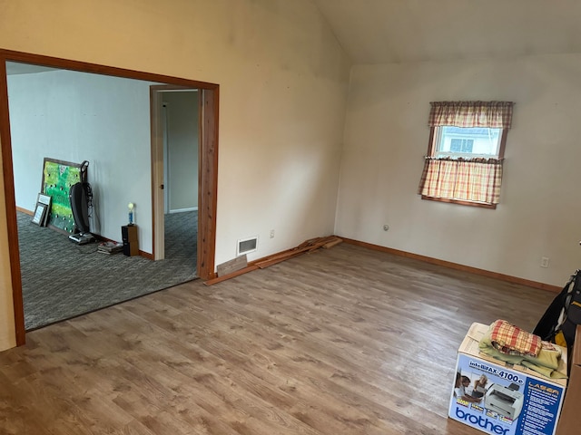 unfurnished room with lofted ceiling and wood-type flooring