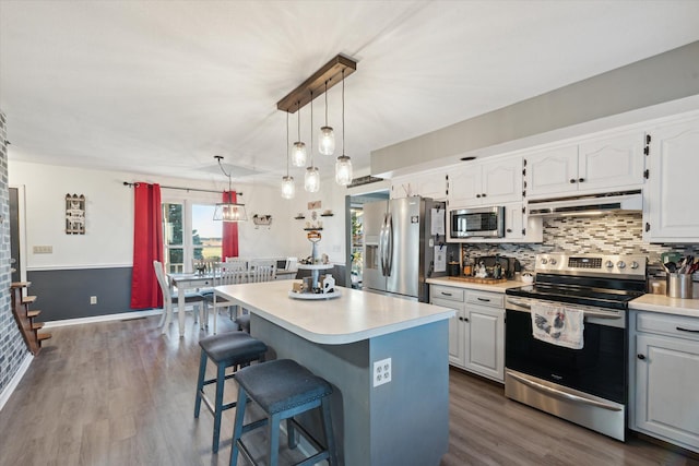 kitchen featuring dark hardwood / wood-style floors, white cabinets, stainless steel appliances, and a kitchen island