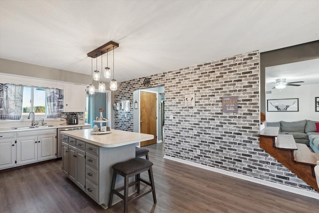 kitchen featuring dark hardwood / wood-style floors, a kitchen breakfast bar, brick wall, a center island, and white cabinets