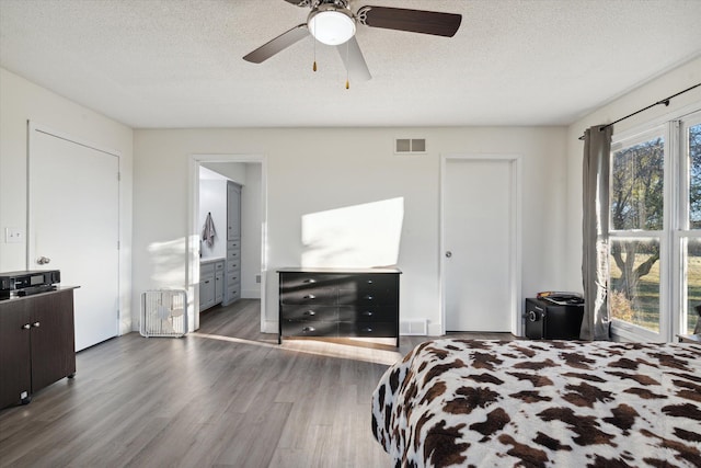 bedroom featuring dark hardwood / wood-style flooring, a textured ceiling, ensuite bath, and ceiling fan