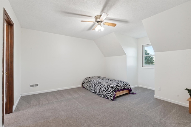 carpeted bedroom featuring ceiling fan, a textured ceiling, and lofted ceiling