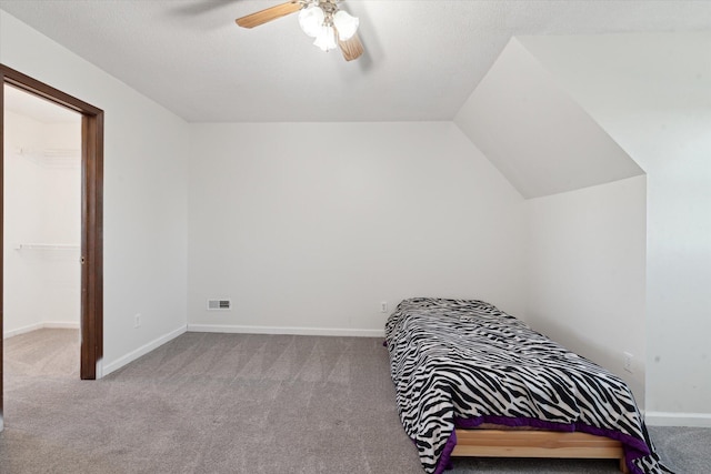 bedroom featuring a spacious closet, light colored carpet, vaulted ceiling, and ceiling fan