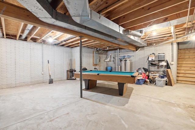 basement with pool table, electric panel, and brick wall