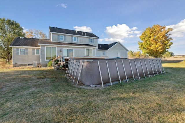 rear view of property featuring central AC and a lawn