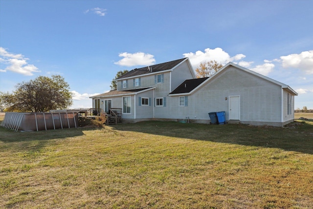 back of property with a lawn and a pool