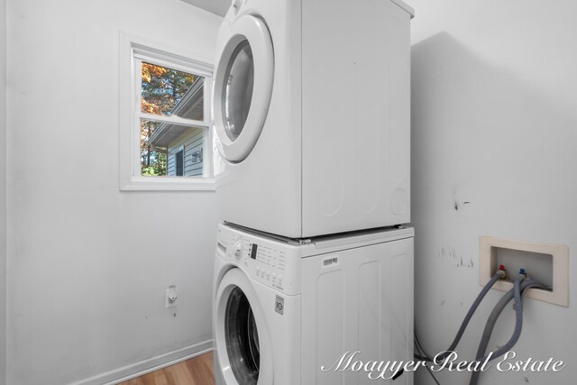 clothes washing area with stacked washer and dryer and light wood-type flooring