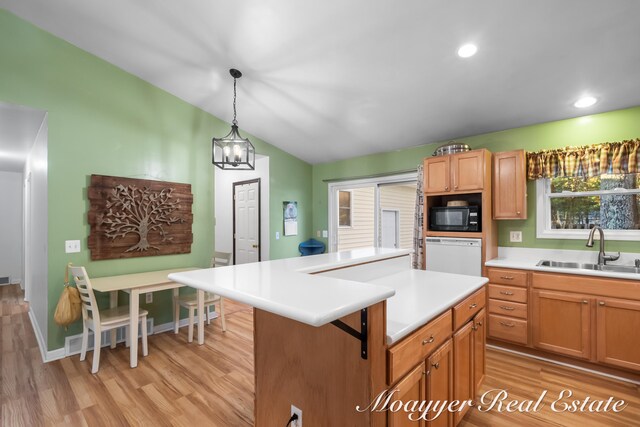 kitchen featuring black microwave, sink, light wood-type flooring, and pendant lighting