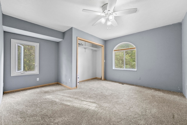 unfurnished bedroom with multiple windows, light colored carpet, and ceiling fan