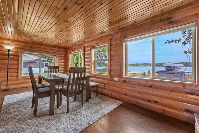 dining space with a water view, wood-type flooring, wooden ceiling, and rustic walls