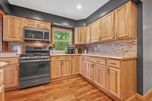 kitchen with decorative backsplash, appliances with stainless steel finishes, light hardwood / wood-style floors, and light brown cabinets