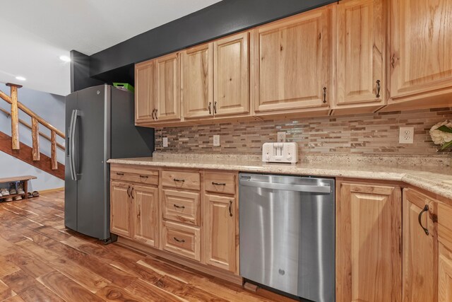 kitchen featuring light stone countertops, appliances with stainless steel finishes, decorative backsplash, light brown cabinets, and dark hardwood / wood-style floors